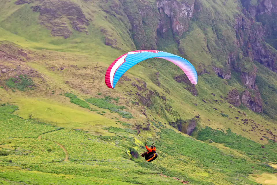 A paraglider over green hills near Mussoorie