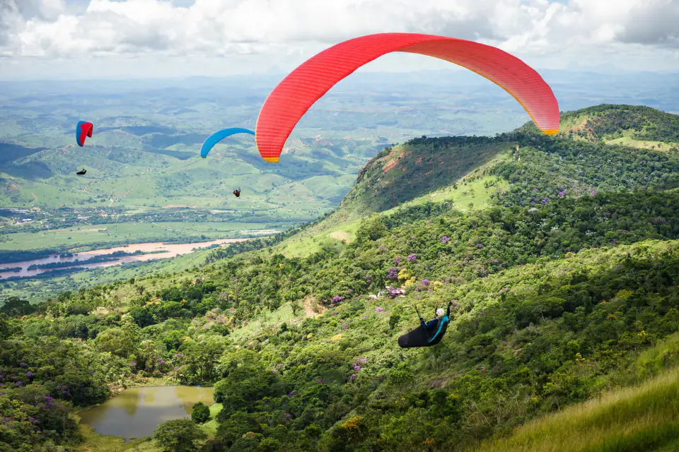 Paragliders over green ridges and a valley