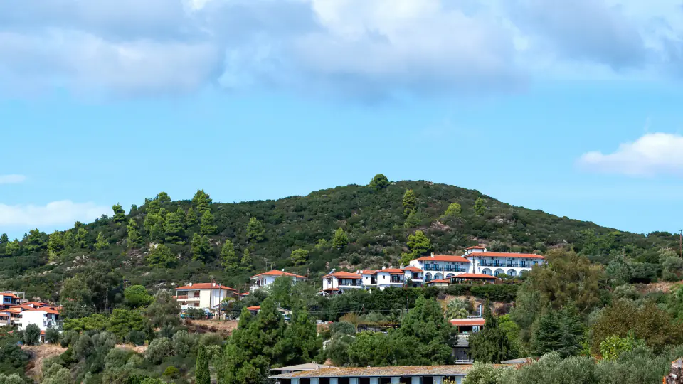 White hillside homes among trees on a green ridge in Mussoorie