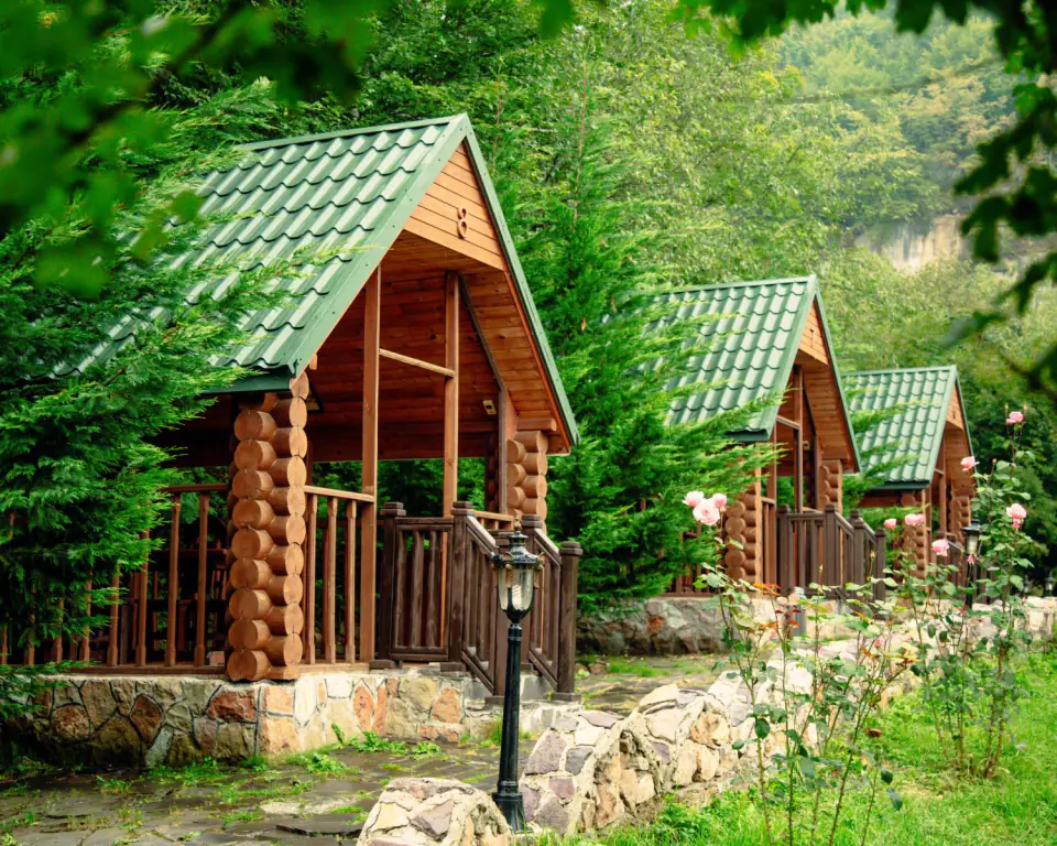Timber cottages with green roofs among trees on a hillside